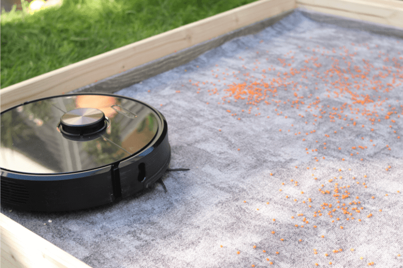 Roborock S6 на тестовой арене на ковре с коротким ворсом во время теста на всасывание чечевицы.